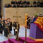 Photographers and reporters can be seen in background, upper right, with the coffin of Queen Elizabeth II on the catafalque in Westminster Hall, London, Wednesday Sept. 14, 2022. Plans by news organizations that have been in place for years — even decades — to cover the death of Queen Elizabeth II were triggered and tested when the event took place. London has been inundated with journalists, with more headed to the city for the funeral services on Monday. ( Jacob King/Pool via AP, File)