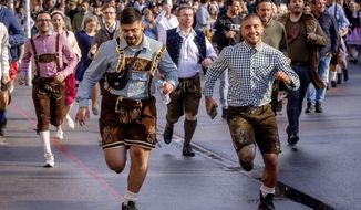 People run onto the festival ground on the opening day of the 187th Oktoberfest beer festival in Munich, Germany, Saturday, Sept. 17, 2022. Oktoberfest is back in Germany after two years of pandemic cancellations, the same bicep-challenging beer mugs, fat-dripping pork knuckles, pretzels the size of dinner plates, men in leather shorts and women in cleavage-baring traditional dresses. (AP Photo/Michael Probst)