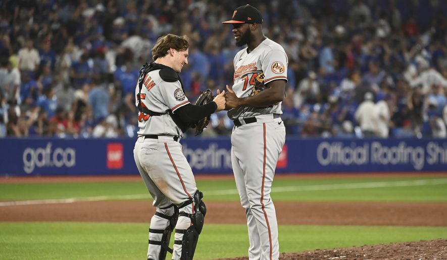 Baltimore Orioles closing pitcher Felix Bautista, right, and catcher Adley Rutschman celebrate their victory over the Toronto Blue Jays in baseball game in Toronto, Sunday, Sept. 18, 2022. (Jon Blacker/The Canadian Press via AP)