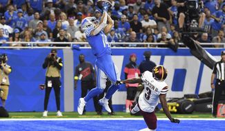 Detroit Lions wide receiver Amon-Ra St. Brown (14) makes a touchdown catch against Washington Commanders cornerback William Jackson III (3) during the first half of an NFL football game Sunday, Sept. 18, 2022, in Detroit. (AP Photo/Lon Horwedel)