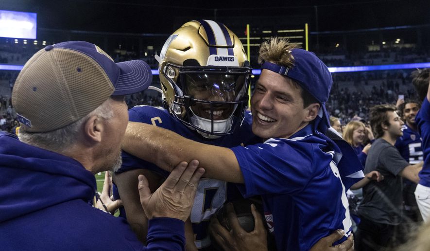 Fans celebrate with Washington quarterback Michael Penix Jr., center, after an NCAA college football game against Michigan State, Saturday, Sept. 17, 2022, in Seattle.  (AP Photo/Stephen Brashear) **FILE**