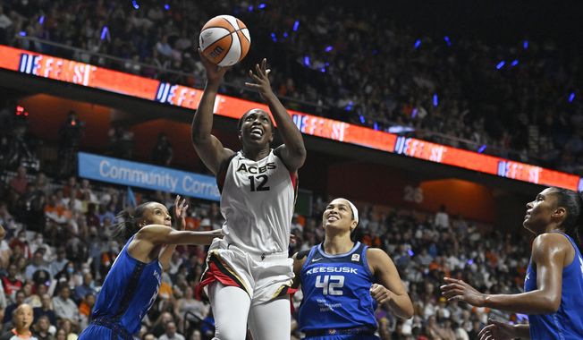 Las Vegas Aces&#x27; Chelsea Gray (12) goes up for a basket as Connecticut Sun&#x27;s DeWanna Bonner, left, and Brionna Jones (42) defend during the second half in Game 4 of a WNBA basketball final playoff series, Sunday, Sept. 18, 2022, in Uncasville, Conn. (AP Photo/Jessica Hill)