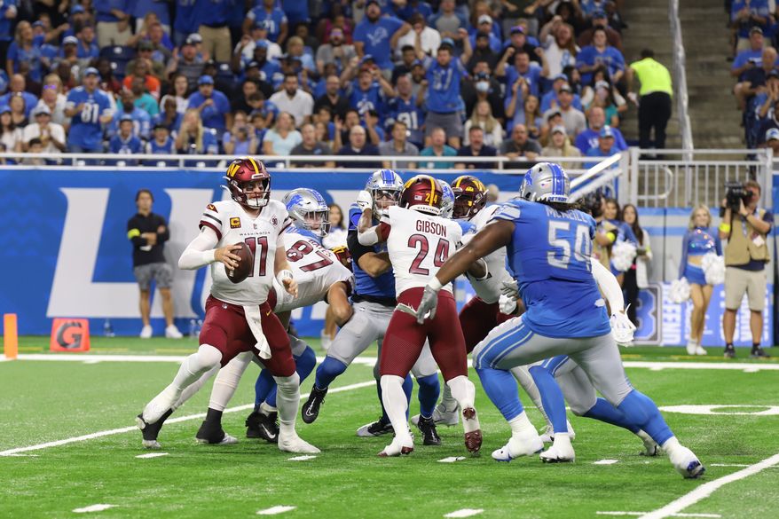Washington Commanders WR Carson Wentz (11) avoiding being tackled, moving out of the pocket with Gibson (24) holding back the Detroit Lions Defensemen at the Commanders vs the Detroit Lions at Ford Field in Detroit Michigan on September 18th 2022 (Photo: Alyssa Howell)