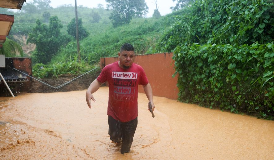A man walks on a road flooded by Hurricane Fiona in Cayey, Puerto Rico, Sunday, Sept. 18, 2022. (AP Photo/Stephanie Rojas)