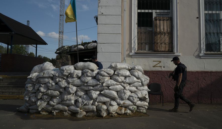 A member of the State Emergency Service of Ukraine enters in the basement of the train station fortified with sand bags that, according to Ukrainian authorities, was used as an interrogation room during the Russian occupation in the retaken village of Kozacha Lopan, Ukraine, Sunday, Sept. 18, 2022. (AP Photo/Leo Correa)