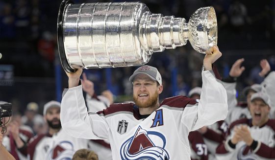 Colorado Avalanche center Nathan MacKinnon lifts the Stanley Cup after the team defeated the Tampa Bay Lightning in Game 6 of the NHL hockey Stanley Cup Finals on Sunday, June 26, 2022, in Tampa, Fla. The Colorado Avalanche are making Nathan MacKinnon the highest-paid player in the NHL’s salary cap era. MacKinnon, who just turned 27 earlier this month, signed an eight-year contract that is worth $100.8 million, according to a person with knowledge of the situation. The person spoke to The Associated Press on condition of anonymity Tuesday, Sept. 20, 2022, because the team did not announce terms of the contract. (AP Photo/Phelan M. Ebenhack, File) **FILE**