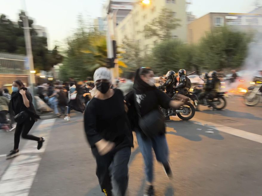In this Monday, Sept. 19, 2022, photo taken by an individual not employed by the Associated Press and obtained by the AP outside Iran, women run away from anti-riot police during a protest of the death of a young woman who had been detained for violating the country&#39;s conservative dress code, in downtown Tehran, Iran. (AP Photo)