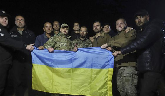 In this photo provided by the Ukrainian Security service Press Office, Ukrainian soldiers released in a prisoner exchange between Russia and Ukraine, hold the Ukrainian flag close to Chernihiv, Ukraine, late Wednesday, Sept. 21, 2022. Ukraine announced a high-profile prisoner swap early Thursday that culminated months of efforts to free many of the Ukrainian fighters who defended a steel plant in Mariupol during a long Russian siege. (Ukrainian Security service Press Office via AP)