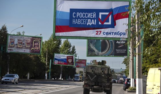 A military vehicle drives along a street with a billboard that reads: &quot;With Russia forever, September 27,&quot; prior to a referendum in Luhansk, Luhansk People&#39;s Republic controlled by Russia-backed separatists, eastern Ukraine, Thursday, Sept. 22, 2022. Four occupied regions in Ukraine are set to start voting Friday Sept. 23, 2022 in Kremlin-engineered referendums on whether to become part of Russia, setting the stage for Moscow to annex the areas in a sharp escalation of the nearly seven-month war. (AP Photo/File)
