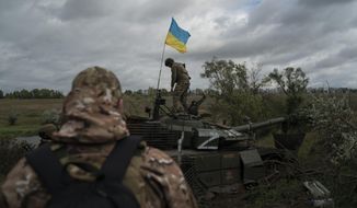 A Ukrainian national guard serviceman stands atop a destroyed Russian tank in an area near the border with Russia, in Kharkiv region, Ukraine, Sept. 19, 2022. A swift Ukrainian counteroffensive earlier this month that forced Russian troops to retreat from broad swaths of the northeastern Kharkiv region has forced the Kremlin to rush absorbing Russia-held areas in Ukraine&#39;s east and south. (AP Photo/Leo Correa, File)