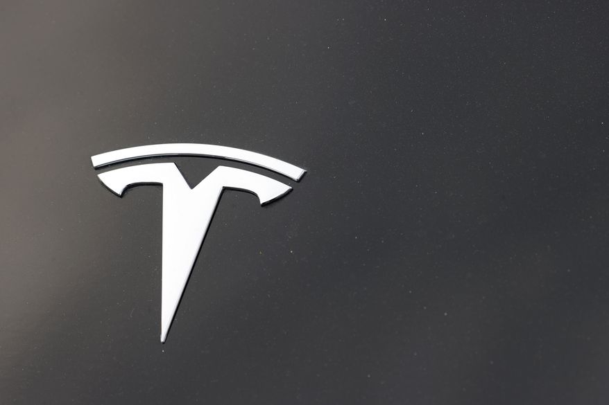 FILE - The Tesla company logo is seen on the hood of an unsold vehicle at a dealership, Sunday, Aug. 9, 2020, in Littleton, Colo. Tesla is recalling nearly 1.1 million vehicles in the U.S. because the windows can pinch a person’s fingers when being rolled up. Tesla says in documents posted Thursday, Sept. 22, 2022 by U.S. safety regulators that the automatic window reversal system may not react correctly after detecting an obstruction.  (AP Photo/David Zalubowski, File)