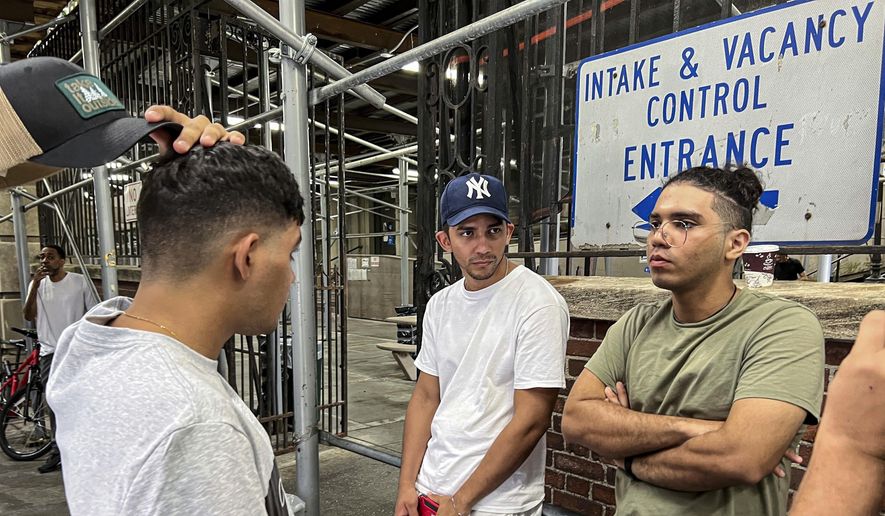 Axel Coronado, center, listens to a conversation between brothers Leonardo Oviedo, left, and Angel Mota, Aug. 10, 2022, in New York. Coronado has been staying at a New York City shelter after fleeing Venezuela to escape his country&#39;s regime and to seek a better a life in the United States. New York City&#39;s mayor says he plans to erect hangar-sized tents as temporary shelter for thousands of international migrants who have been bused into the Big Apple as part of a campaign by Republican governors to disrupt federal border policies. (AP Photo/Bobby Caina Calvan, File)
