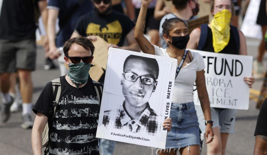 FILE - A demonstrator carries an image of Elijah McClain during a rally and march in Aurora, Colo., June 27, 2020. A Colorado judge on Friday, Sept. 16, 2022 responded to a request by a coalition of news organizations to release an amended autopsy report for Elijah McClain, a 23-year-old Black man who died after a 2019 encounter with police, by ruling the report be made public only after new information it contains is redacted. (AP Photo/David Zalubowski, File)