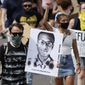 FILE - A demonstrator carries an image of Elijah McClain during a rally and march in Aurora, Colo., June 27, 2020. A Colorado judge on Friday, Sept. 16, 2022 responded to a request by a coalition of news organizations to release an amended autopsy report for Elijah McClain, a 23-year-old Black man who died after a 2019 encounter with police, by ruling the report be made public only after new information it contains is redacted. (AP Photo/David Zalubowski, File)