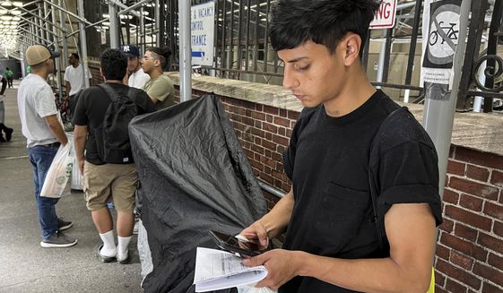 FILE — Dilan Jimenez reads text messages as he stands outside a shelter, after arriving on a chartered bus from Texas earlier in the day, Aug. 10, 2020, in New York. New York City&#39;s mayor says he plans to erect hangar-sized tents as temporary shelter for thousands of international migrants who have been bused into the Big Apple as part of a campaign by Republican governors to disrupt federal border policies. (AP Photo/Bobby Caina Calvan)
