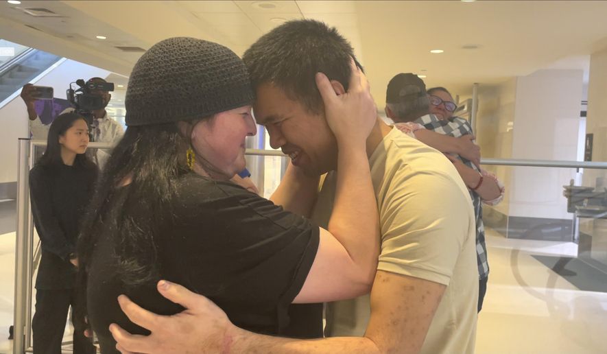 Andy Huynh, left, and Alex Drueke, far right, are seen hugging their loved ones after arriving at Birmingham-Shuttlesworth International Airport in Birmingham, Ala., Saturday, Sept. 24, 2022. The U.S. military veterans disappeared three months ago while fighting Russia with Ukrainian forces. They were released earlier this week by Russian-backed separatists as part of a prisoner exchange. (AP Photo/Kim Chandler)