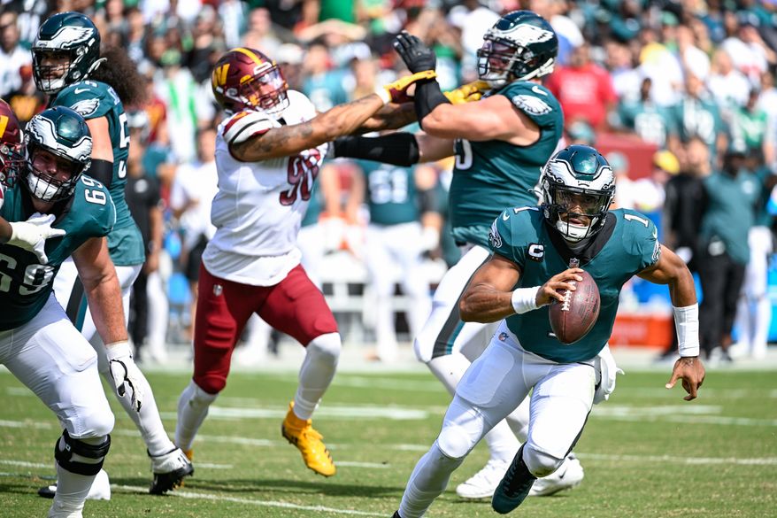 Philadelphia Eagles quarterback Jalen Hurts (1) scrambles away from Washington Commanders defensive end Montez Sweat during the first quarter against the Philadelphia Eagles at FedEx Field, Landover, MD, September 25, 2022. (Photo by Brian Murphy)
