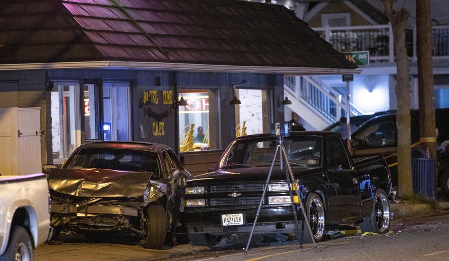 A sedan is wedged between a small, black pickup truck and the Bagel Time Cafe in Wildwood, N.J., early Sunday, Sept. 25, 2022. Authorities say at least two people were killed amid multiple crashes at a pop-up car rally. (Dave Hernandez/NJ Advance Media via AP)