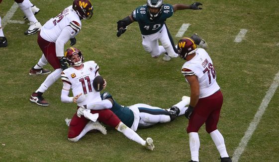 Washington Commanders quarterback Carson Wentz (11) is sacked by Philadelphia Eagles defensive end Josh Sweat (94) during the second half of an NFL football game, Sunday, Sept. 25, 2022, in Landover, Md. (AP Photo/Nick Wass)