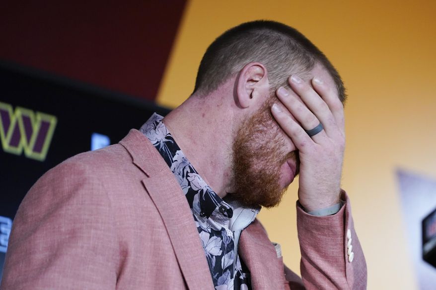 Washington Commanders quarterback Carson Wentz (11) covers his face during his news conference after and an NFL football game against the Philadelphia Eagles, Sunday, Sept. 25, 2022, in Landover, Md. Eagles won 24-8. (AP Photo/Alex Brandon)