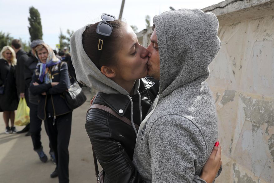 A Russian recruit and his wife kiss and hug each other outside a military recruitment center in Volgograd, Russia, Saturday, Sept. 24, 2022. Russian President Vladimir Putin on Wednesday ordered a partial mobilization of reservists to beef up his forces in Ukraine. (AP Photo)