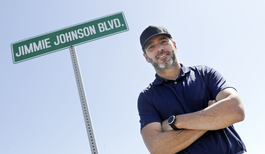 Driver Jimmie Johnson poses in front of a street sign after the street was named for him outside Kentucky Speedway before a NASCAR Cup Series auto race Sunday, July 12, 2020, in Sparta, Ky.  The Seven-time NASCAR champion is retiring from full-time racing and will turn his focus toward spending time with family. He figures his future schedule will include no more than 10 bucket list events and has his sights set on the 24 Hours of Le Mans. (AP Photo/Mark Humphrey, File) **FILE**