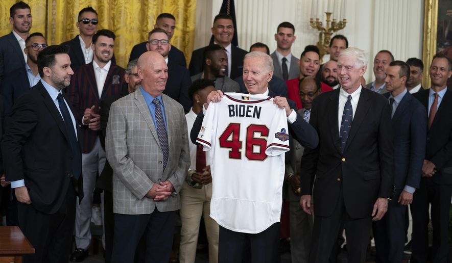 President Joe Biden holds up a jersey during an event celebrating the 2021 World Series champion Atlanta Braves, in the East Room of the White House, Monday, Sept. 26, 2022, in Washington. From left, Braves President of Baseball Operations Alex Anthopoulos, manager Brian Snitker, Biden, and Braves President and CEO Terry McGuirk. (AP Photo/Evan Vucci)