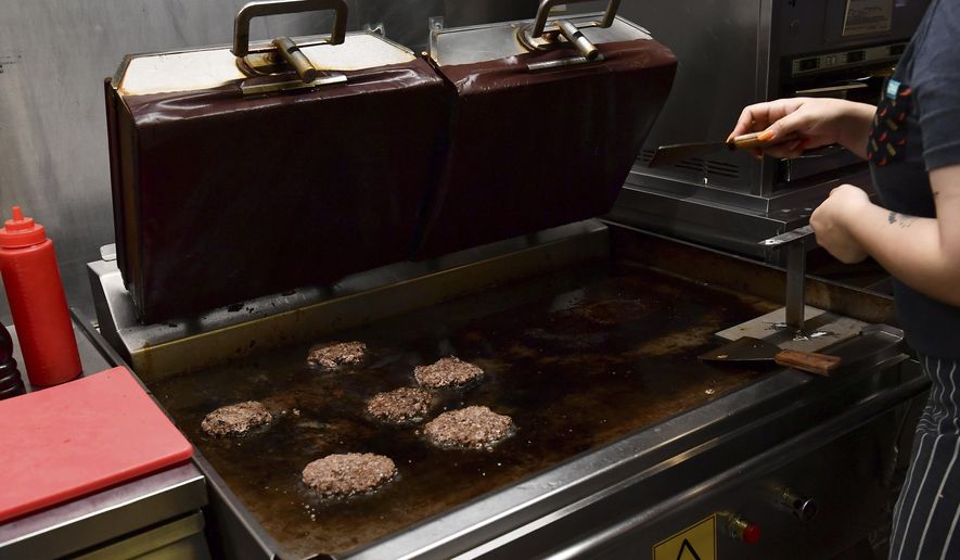 A worker cooks burgers at Zing Burger store in Budapest, Hungary, Monday, Sept. 12, 2022. Richard Kovacs, a business development manager for the Hungarian burger chain, said some of the chain&#39;s 15 stores have seen a 750% increase in electricity bills since the beginning of the year — leading to additional monthly costs of up to 1.5 million Hungarian forints ($3,840) per store. (AP Photo/Anna Szilagyi)