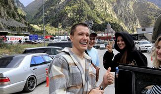 A group of Russians smile at the border crossing Verkhny Lars between Georgia and Russia on Friday, Sept. 23, 2022. Long lines of vehicles have formed at a border crossing between Russia&#x27;s North Ossetia region and Georgia after Moscow announced a partial military mobilization. A day after President Vladimir Putin ordered a partial mobilization to bolster his troops in Ukraine, many Russians are leaving their homes. (AP Photo/Shakh Aivazov, File)