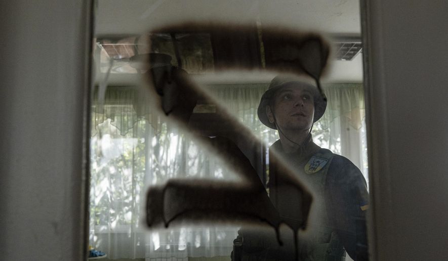 A Ukrainian serviceman inspects a kindergarten classroom with a sign "Z" on the door that was used by Russian forces in the recently retaken area of Kapitolivka, Ukraine, Sunday, Sept. 25, 2022. (AP Photo/Evgeniy Maloletka)