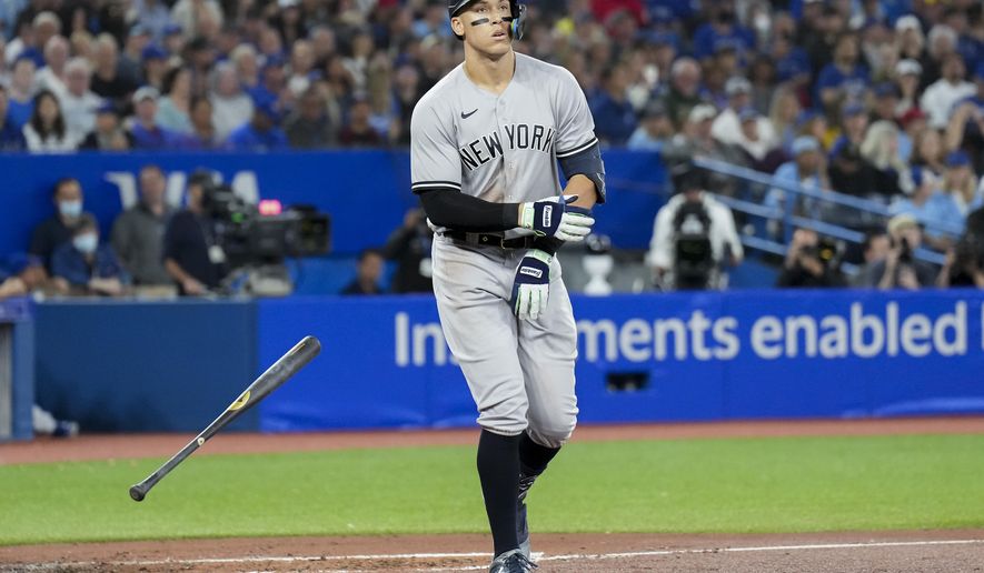 New York Yankees&#x27; Aaron Judge tosses his bat as he is walked by Toronto Blue Jays starting pitcher Kevin Gausman during third-inning baseball game action in Toronto, Monday, Sept. 26, 2022. (Nathan Denette/The Canadian Press via AP)