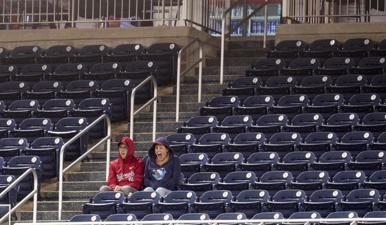 Two Washington Nationals fans sit and watch the game against the Atlanta Braves surrounded by empty seats during the ninth inning of a baseball game at Nationals Park, Tuesday, Sept. 27, 2022, in Washington. The Braves won 8-2. (AP Photo/Jess Rapfogel)
