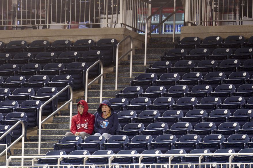 Two Washington Nationals fans sit and watch the game against the Atlanta Braves surrounded by empty seats during the ninth inning of a baseball game at Nationals Park, Tuesday, Sept. 27, 2022, in Washington. The Braves won 8-2. (AP Photo/Jess Rapfogel)