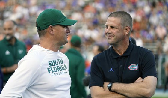 South Florida head coach Jeff Scott, left, and Florida head coach Billy Napier greet each other at midfield before an NCAA college football game, Saturday, Sept. 17, 2022, in Gainesville, Fla. (AP Photo/John Raoux) **FILE**