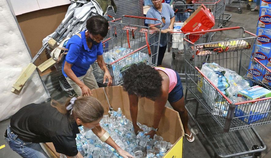 Shoppers at the Costco store in Altamonte Springs, Fla. grab bottles of water from the last pallet in stock on Monday, Sept. 26, 2022, as Central Floridians prepare for the impact of Hurricane Ian. (Joe Burbank/Orlando Sentinel via AP)