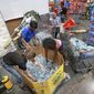 Shoppers at the Costco store in Altamonte Springs, Fla. grab bottles of water from the last pallet in stock on Monday, Sept. 26, 2022, as Central Floridians prepare for the impact of Hurricane Ian. (Joe Burbank/Orlando Sentinel via AP)