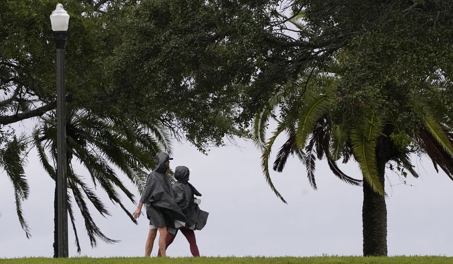 A couple walks along the waterfront that is seeing the effects of Hurricane Ian Wednesday, Sept. 28, 2022, in Saint Petersburg, Fla. (AP Photo/Steve Helber)