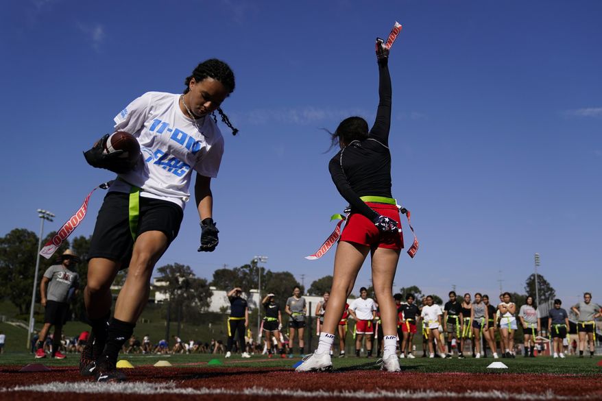 Elsa Morin, 17, right, holds up a flag she pulled from Aaliyah Young, 17, left, as they try out for the Redondo Union High School girls flag football team on Thursday, Sept. 1, 2022, in Redondo Beach, Calif. Southern California high school sports officials will meet on Thursday, Sept. 29, to consider making girls flag football an official high school sport. This comes amid growth in the sport at the collegiate level and a push by the NFL to increase interest. (AP Photo/Ashley Landis)