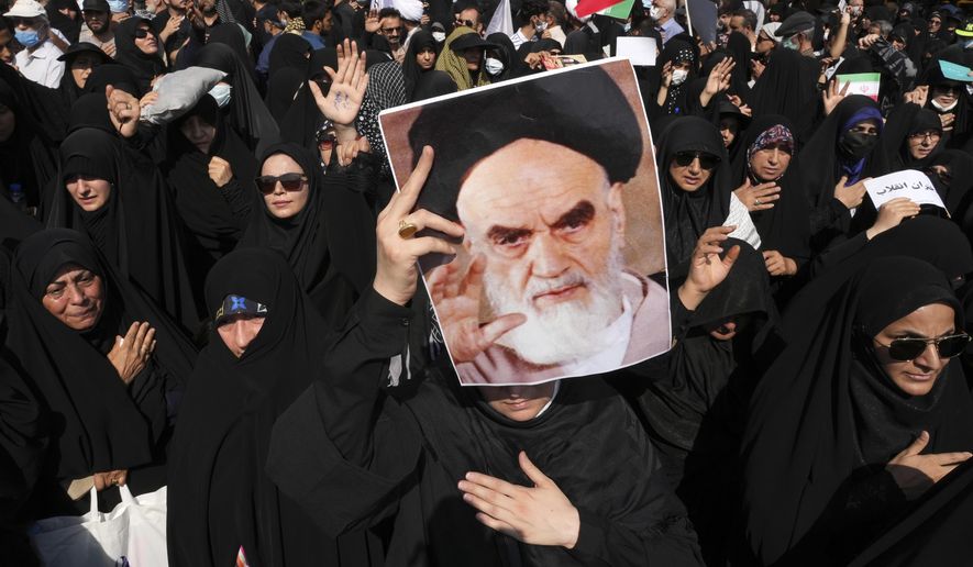 File - A pro-government demonstrator holds a poster of the late Iranian revolutionary founder Ayatollah Khomeini while attending a rally after the Friday prayers to condemn recent anti-government protests over the death of a young woman in police custody, in Tehran, Iran, Friday, Sept. 23, 2022. The crisis unfolding in Iran began as a public outpouring over the the death of Mahsa Amini, a young woman from a northwestern Kurdish town who was arrested by the country&#x27;s morality police in Tehran last week for allegedly violating its strictly-enforced dress code. (AP Photo/Vahid Salemi, File)