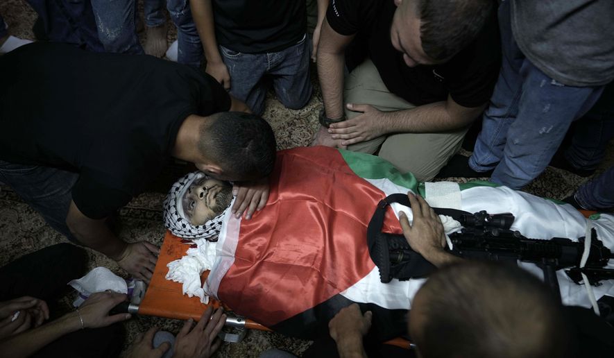 Mourners surround the Palestiian flag-draped body of Muhammad Alawneh, killed during an Israeli military raid in the occupied West Bank town of Jenin, Wednesday, Sept. 28, 2022. At least four Palestinians were killed and dozens of others wounded, the Palestinian Health Ministry reported, the latest in a series of deadly Israeli operations in the occupied territory. (AP Photo/ Majdi Mohammed)