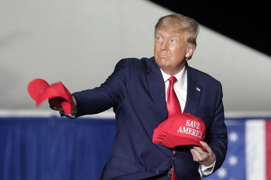 Former President Donald Trump tosses caps to the crowd as he holds a rally Friday, Sept. 23, 2022, in Wilmington, N.C. (AP Photo/Chris Seward)