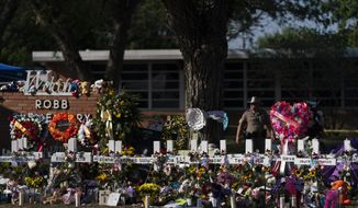 Flowers and candles are placed around crosses on May 28, 2022, at a memorial outside Robb Elementary School in Uvalde, Texas, to honor the victims killed in the school shooting a few days prior. A federal lawsuit was filed Wednesday, Sept. 28, 2022, in Del Rio, Texas, against eight entities and three individuals for the May shooting that killed 19 students and two teachers at the elementary school. (AP Photo/Jae C. Hong, File)