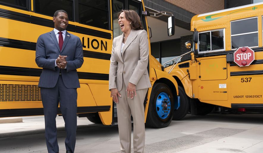 Vice President Kamala Harris, right, laughs with Environmental Protection Agency Administrator Michael Regan, during a tour of electric school buses at Meridian High School in Falls Church, Va., May 20, 2022. The EPA said Thursday, Sept. 29, that it will nearly double, to nearly $1 billion, funding available to states to acquire electric school buses, responding to what it calls overwhelming demand for cleaner school transportation. (AP Photo/Jacquelyn Martin, File)