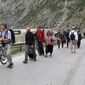 People walk toward the border crossing between Georgia and Russia at Verkhny Lars, as they leave Chmi, North Ossetia–Alania Republic, Russia, Wednesday, Sept. 28, 2022. Long lines of vehicles have formed at a border crossing between Russia&#39;s North Ossetia region and Georgia after Moscow announced a partial military mobilization. (AP Photo)