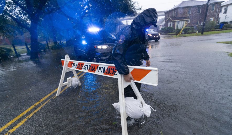 A Charleston police officer moves a barricade to block a flooded street as the effects from Hurricane Ian are felt, Friday, Sept. 30, 2022, in Charleston, S.C. (AP Photo/Alex Brandon)