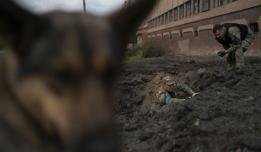 Ukrainian police officers collect fragments from a crater to determine the type of ammunition after a Russian attack in Kramatorsk, Ukraine, Thursday, Sept. 29, 2022. (AP Photo/Leo Correa)