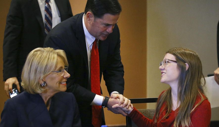 Then-U.S. Education Secretary Betsy DeVos, left, joins Arizona Gov. Doug Ducey, center, as they talk with Grace Jones, a high school sophomore from Tucson, Ariz., after a roundtable discussion on school choice on Dec. 5, 2019, in Scottsdale, Ariz. All Arizona parents now can use state tax money to send their children to private or religious schools or pay homeschooling costs after an effort by public school advocates to block a massive expansion of the state&#39;s private school voucher law failed to collect enough signatures to block the law. (AP Photo/Ross D. Franklin, File)