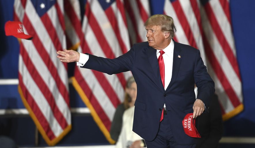 Former President Donald Trump tosses caps to the crowd as he steps onstage during a rally at the Macomb Community College Sports &amp; Expo Center in Warren, Mich., Saturday, Oct. 1, 2022. (Todd McInturf/Detroit News via AP)