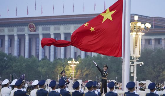 In this photo released by Xinhua News Agency, a member of the Chinese honor guard unfurls the Chinese national flag during a flag raising ceremony to mark the 73rd anniversary of the founding of the People&#39;s Republic of China held at the Tiananmen Square in Beijing on Saturday, Oct. 1, 2022. (Chen Zhonghao/Xinhua via AP)