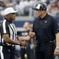 Referee Shawn Smith, left, talks with Washington Commanders head coach Ron Rivera, right, in the first half of a NFL football game against the Dallas Cowboys in Arlington, Texas, Sunday, Oct. 2, 2022. (AP Photo/Michael Ainsworth)